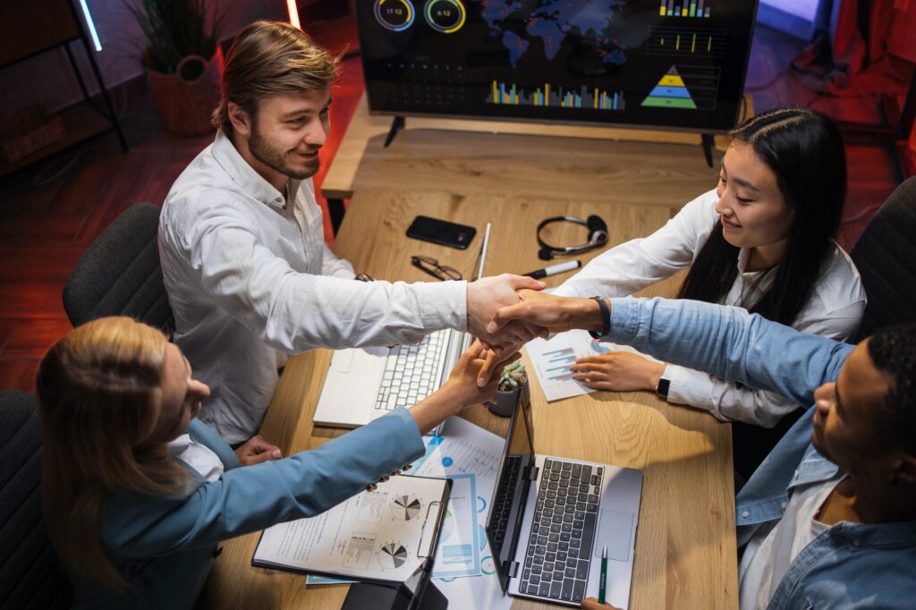 Multi ethnic company workers shaking hands during meeting